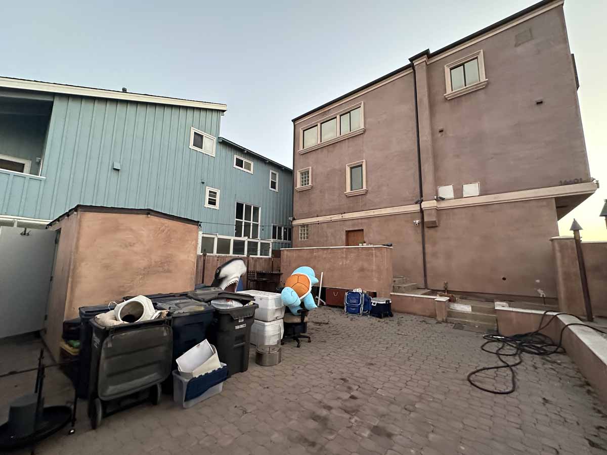 Unfinished and cluttered parking area with home in the background.