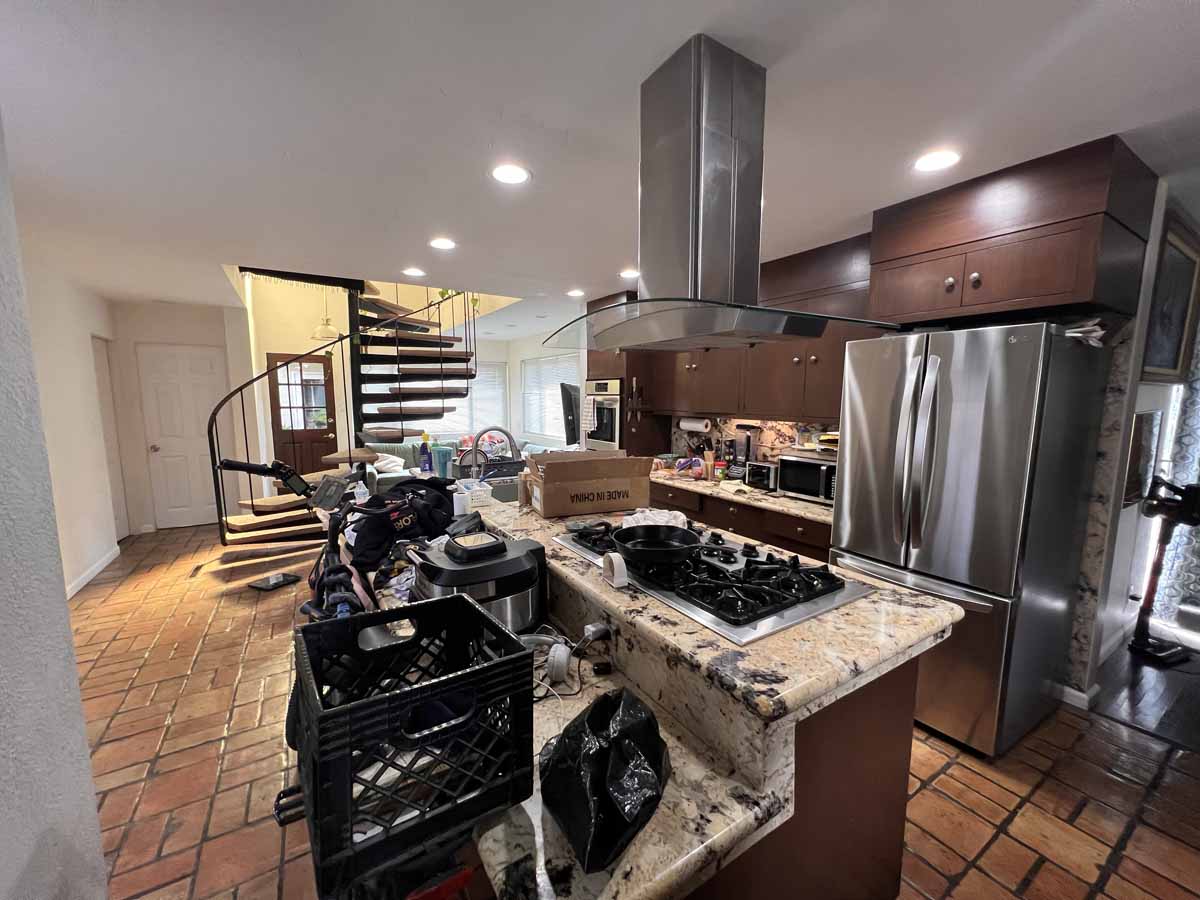 A cluttered kitchen island with a spiral staircase in the background.