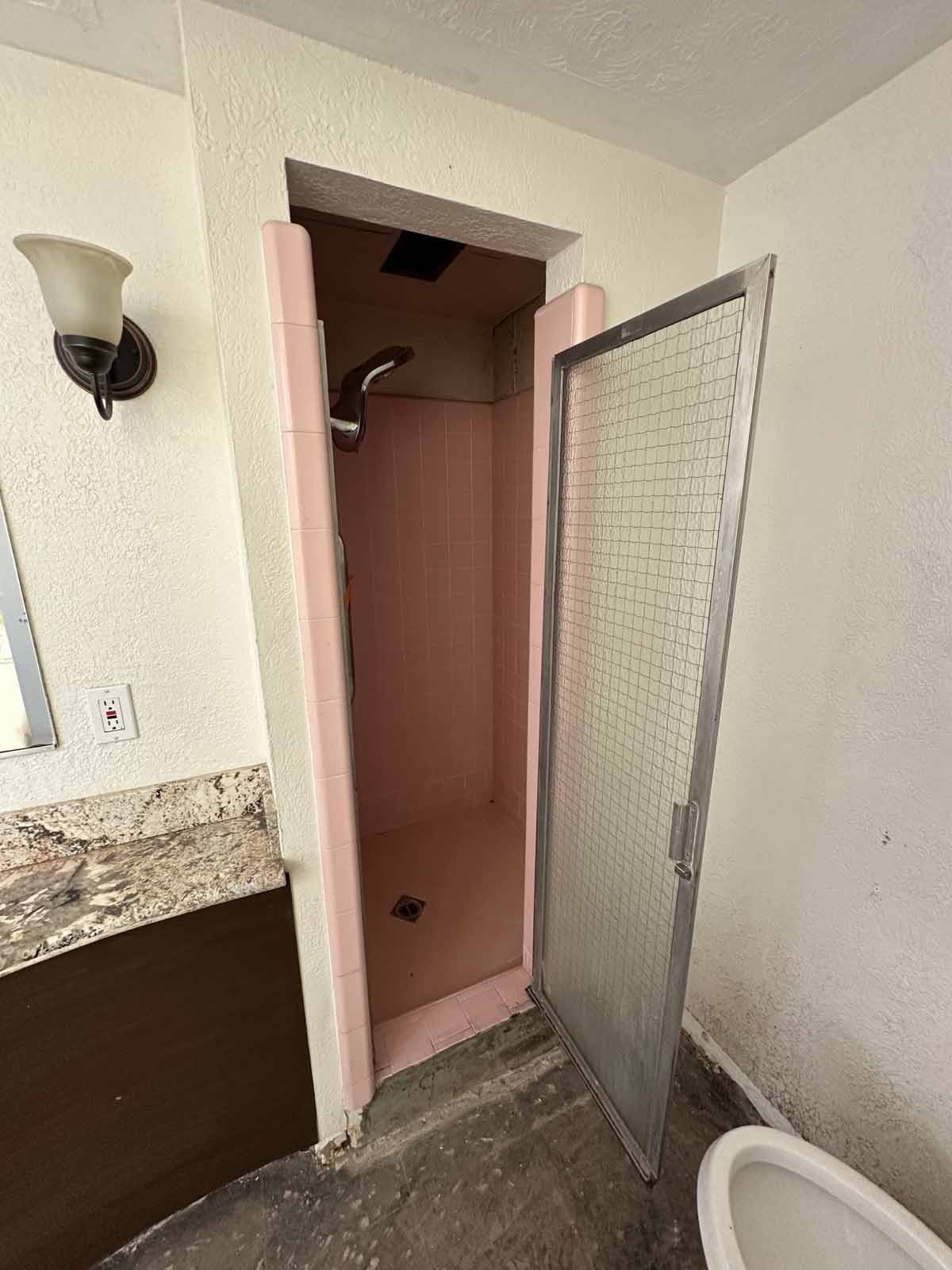 An old outdated pink walk-in shower.