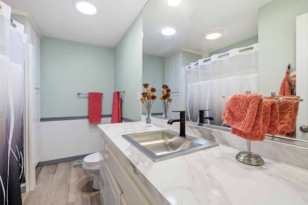 Updated bathroom with large single sink vanity with stone counter, a toilet and a tub/shower combo.