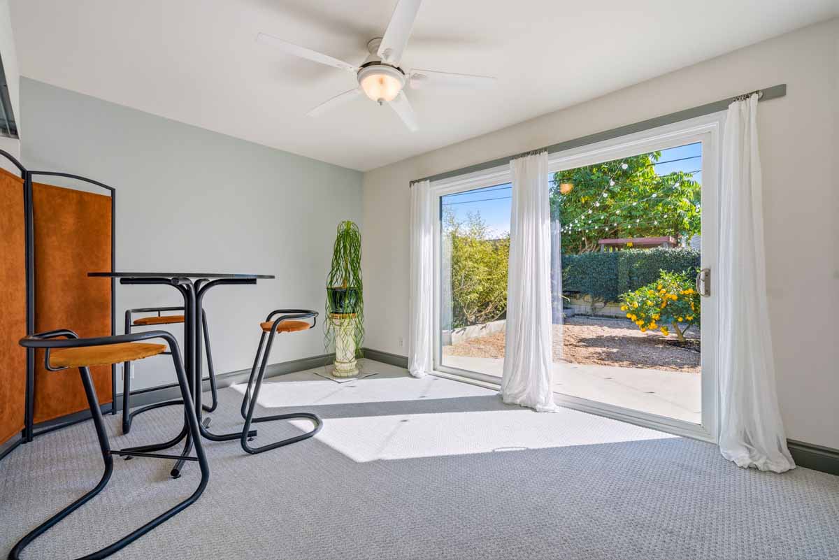 Bedroom with bright light shining through the large sliding glass doors into the neutral-colored room.