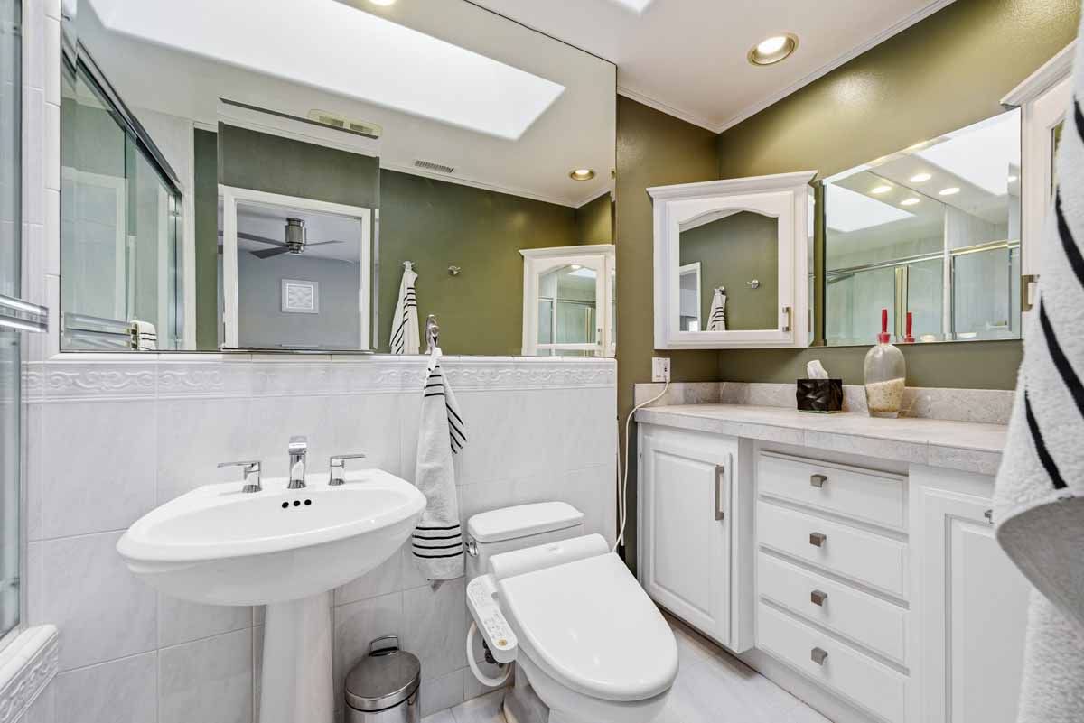 The master bathroom showing a pedestal sink, toilet and storage space.