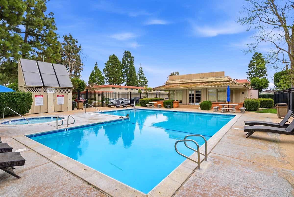 Large community pool with lounge chairs and a building in the background.
