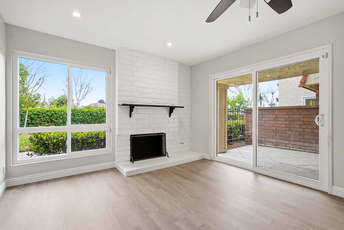 Updated living room with light colored wood-style flooring, a fireplace and lots of windows and recessed lights.