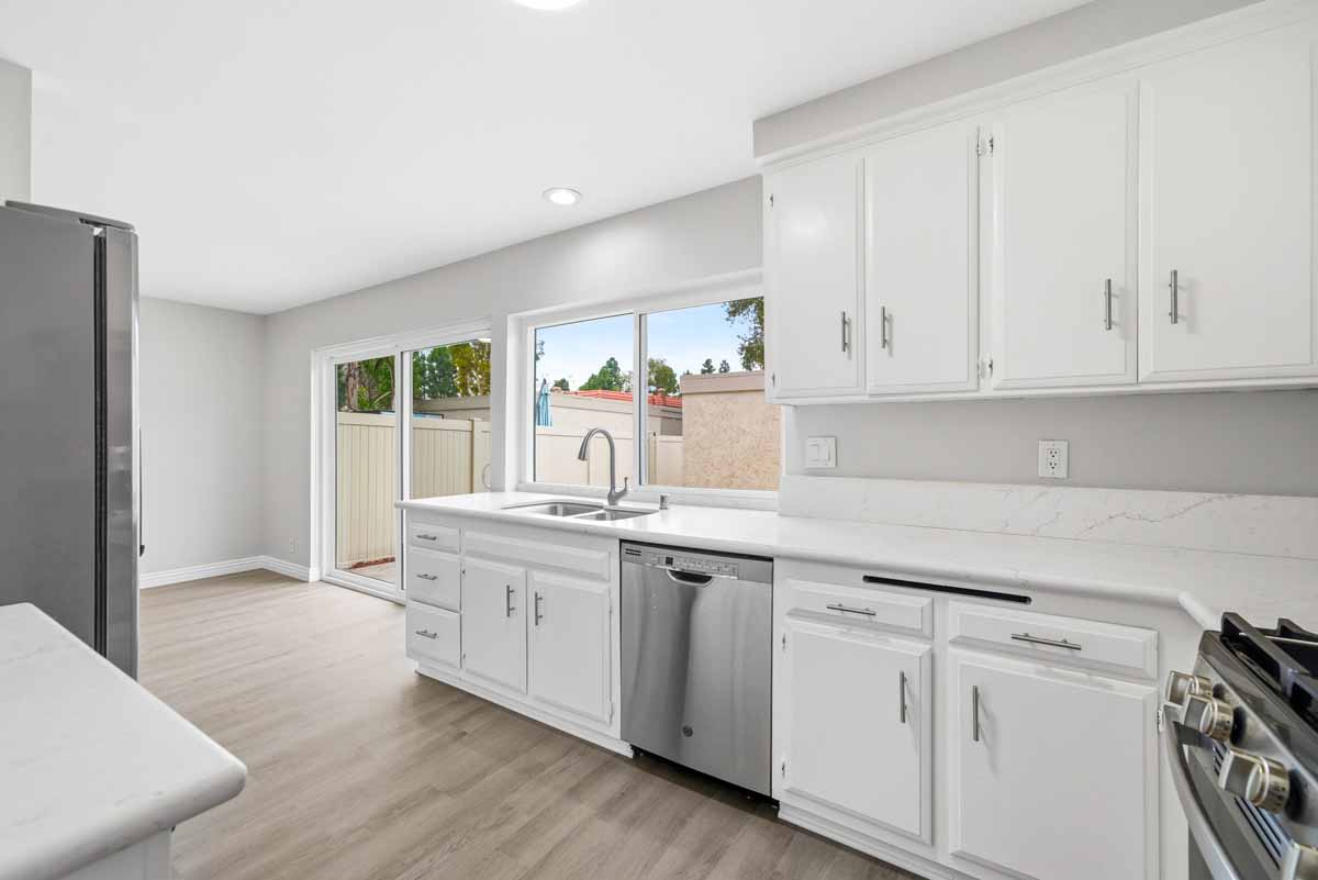 Updated kitchen with white cabinets and stone counter tops, showing sliding glass doors to the side that will lead you to the patio.