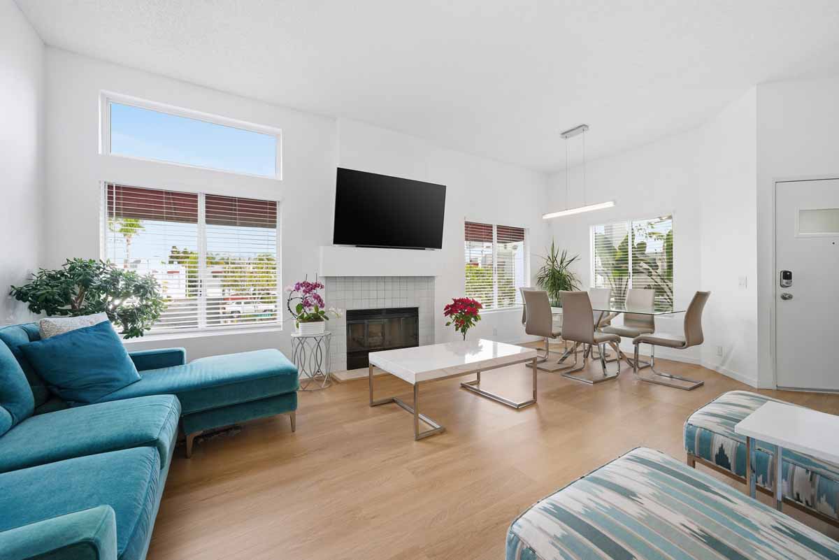 Living room with a tv mounted above the fireplace, a couch and coffee table, and a dining set.