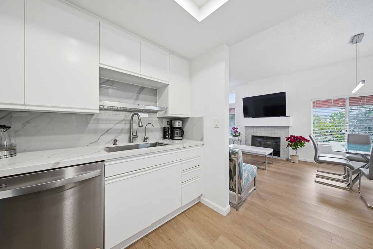Updated kitchen with white cabinets and a neutral stone counter top.