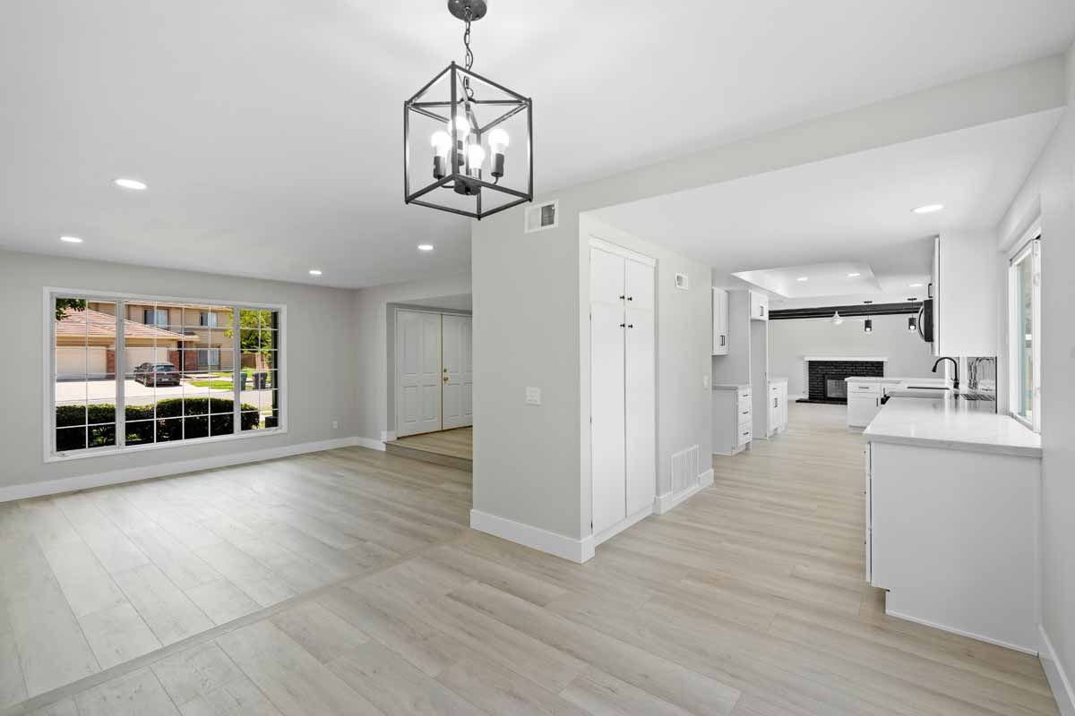Open kitchen, dining and family room leading to the front door. Floors are light wood and walls are a light neutral paint.