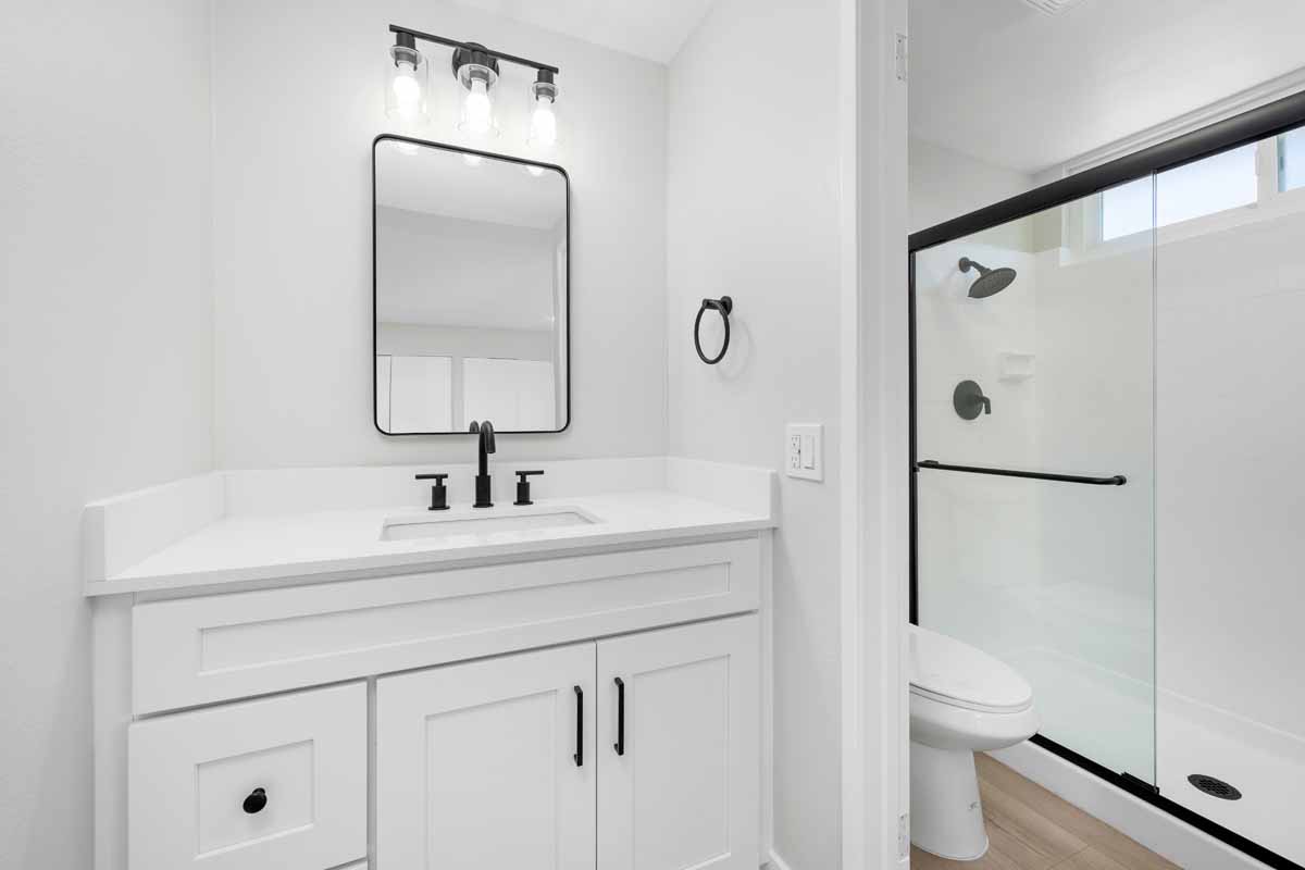 Updated bathroom showing white walls, stone countertop and cabinets with black accents.