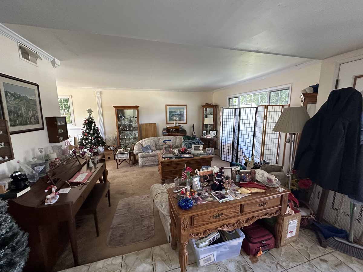 Living room in outdated home with brown carpet and a lot of furniture.