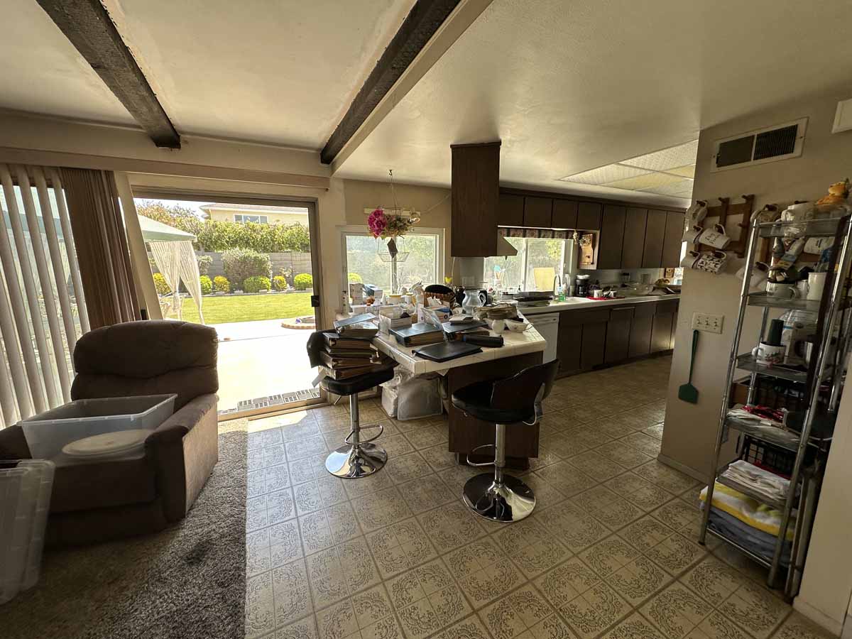 Outdated kitchen with linoleum floors and slider leading to backyard.