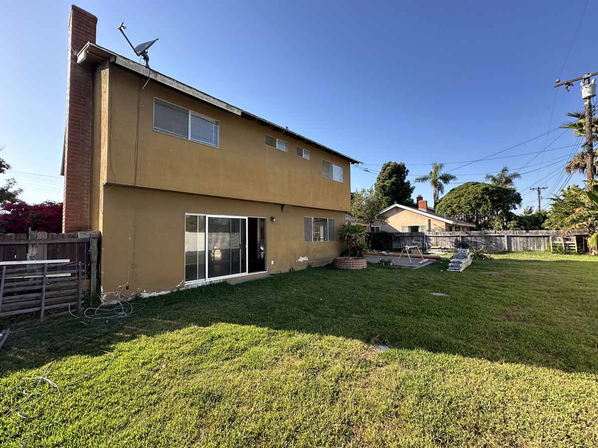 Backyard of 18954 Santa Marta Street showing large grassy area and yellow-toned exterior stucco of home.