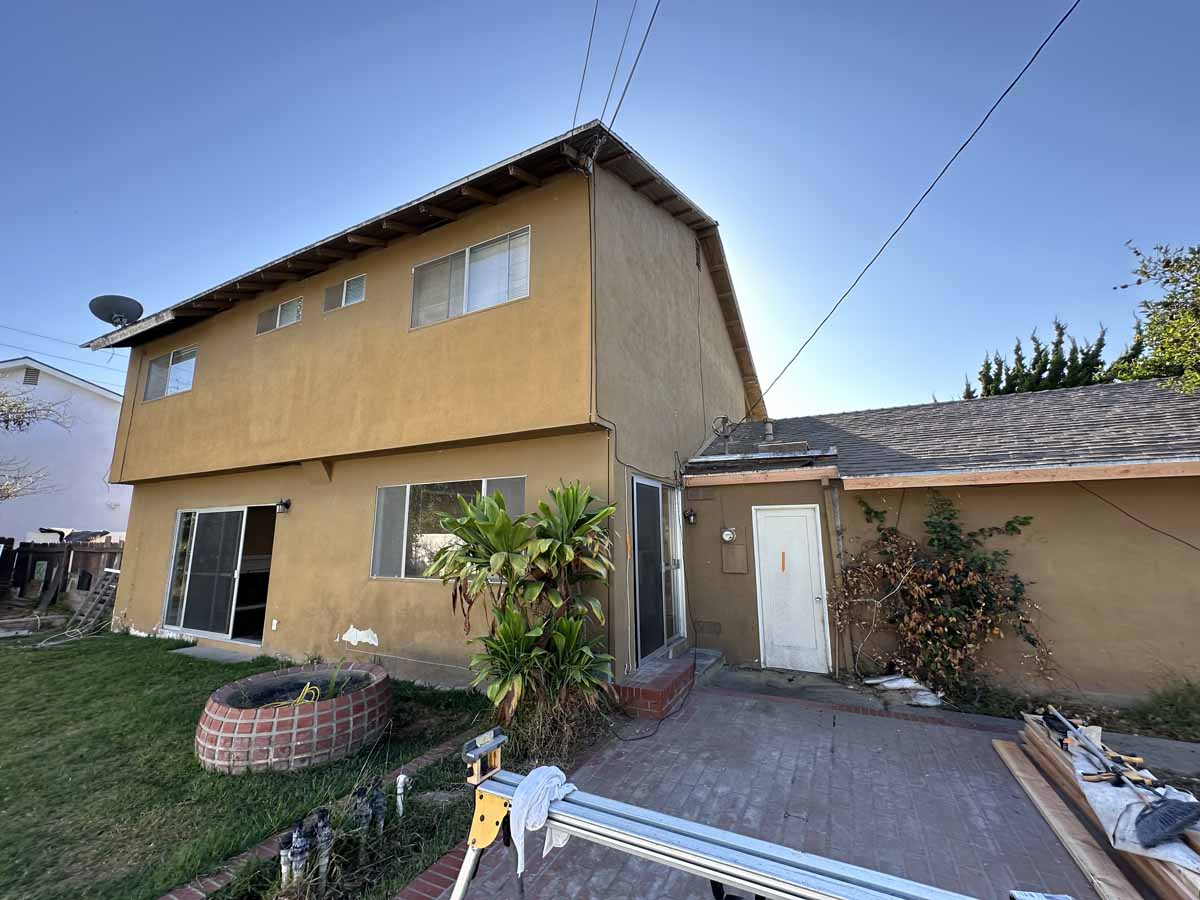 Backyard of 18954 Santa Marta Street showing a grassy area and yellow-toned exterior stucco of home.