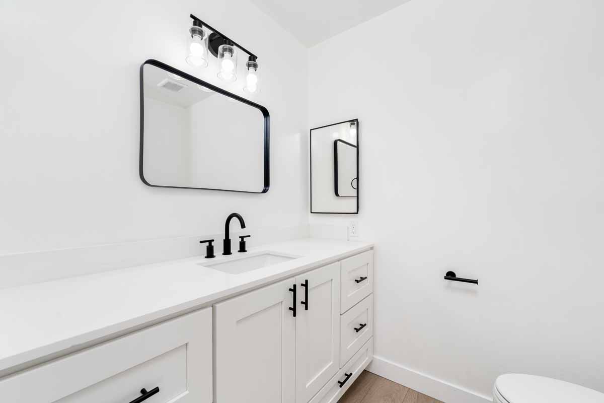 An updated bathroom with white walls, vanity and counters, and black accents.