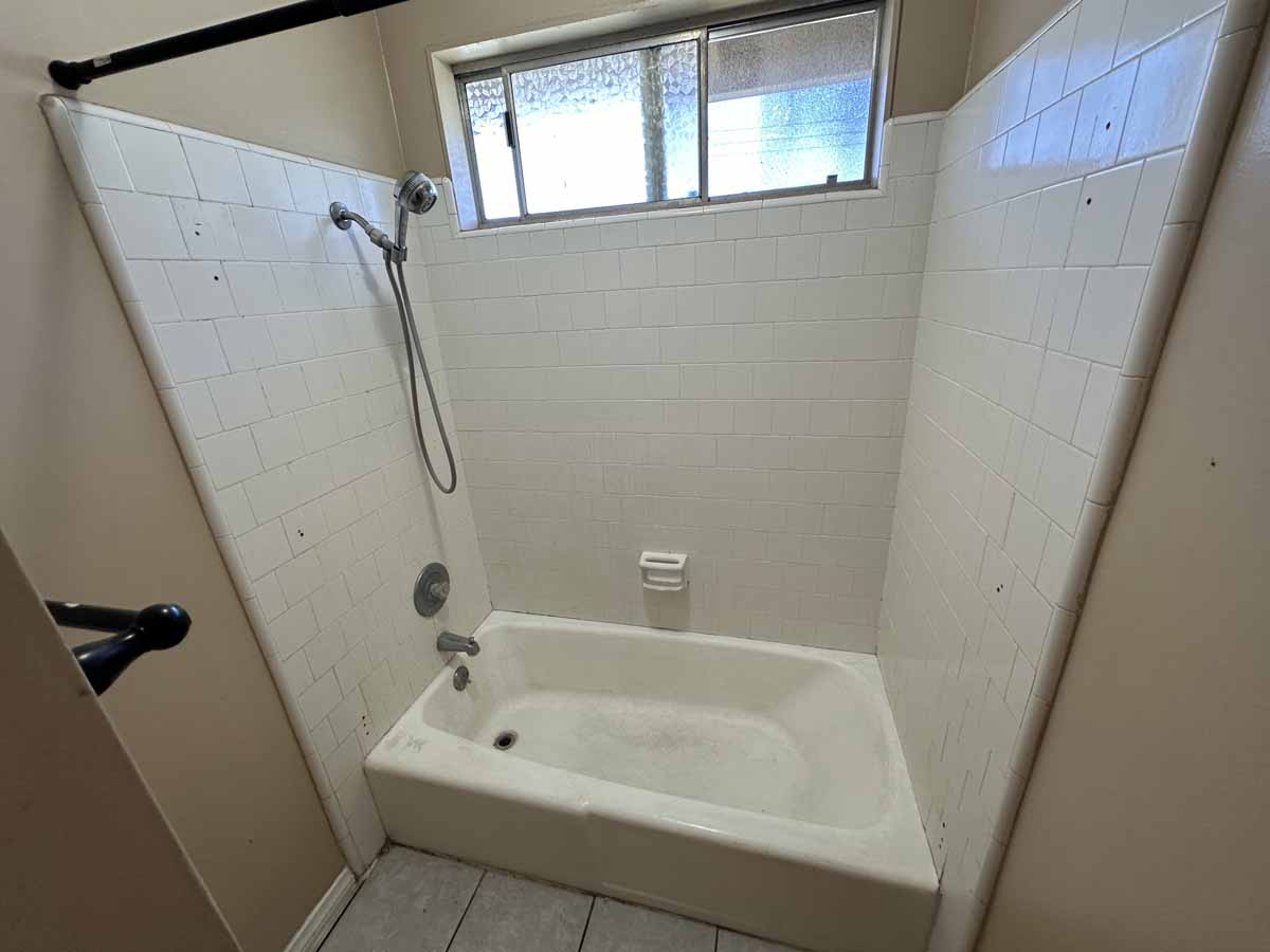 A dirty white shower/bathtub combo.