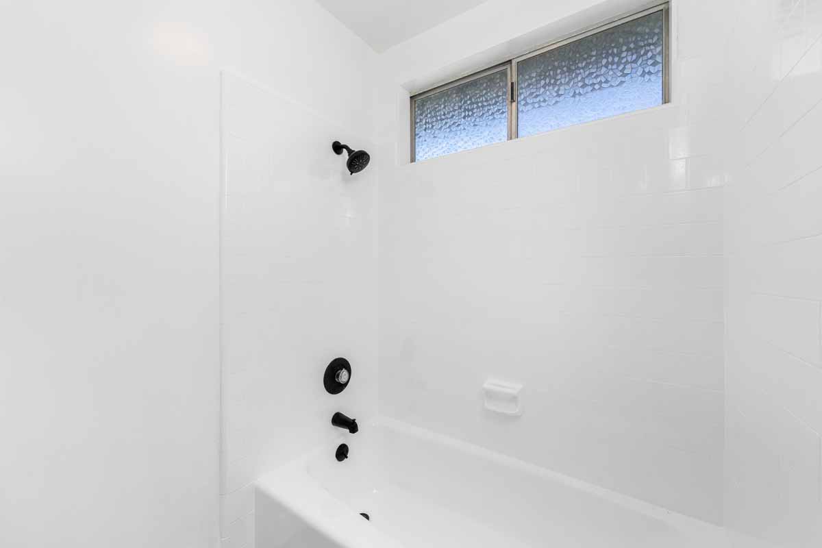 An updated, clean bathroom with a white tub/shower combo.