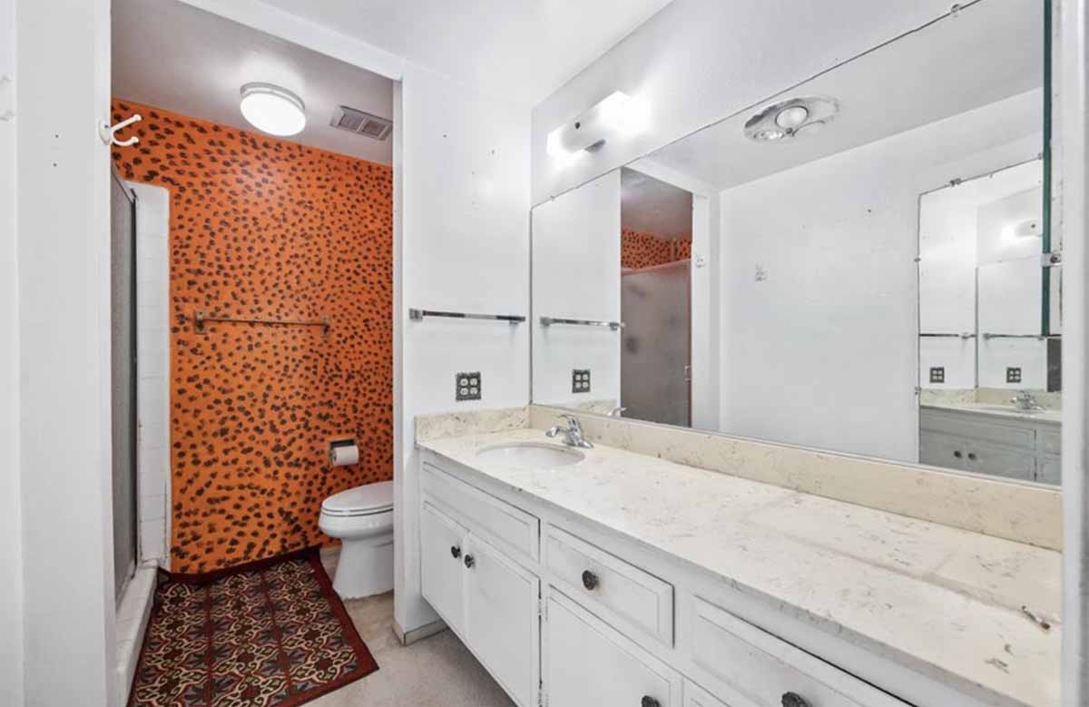 An outdated bathroom with a large vanity and mirror and toilet.
