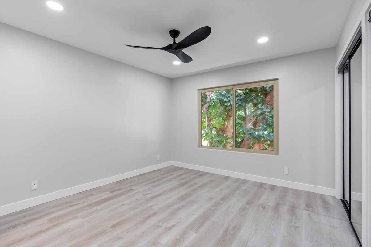 An updated empty bedroom with neutral toned walls and floors, and recessed lighting.