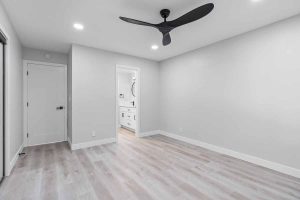 An updated empty bedroom with neutral toned walls and floors, and recessed lighting.
