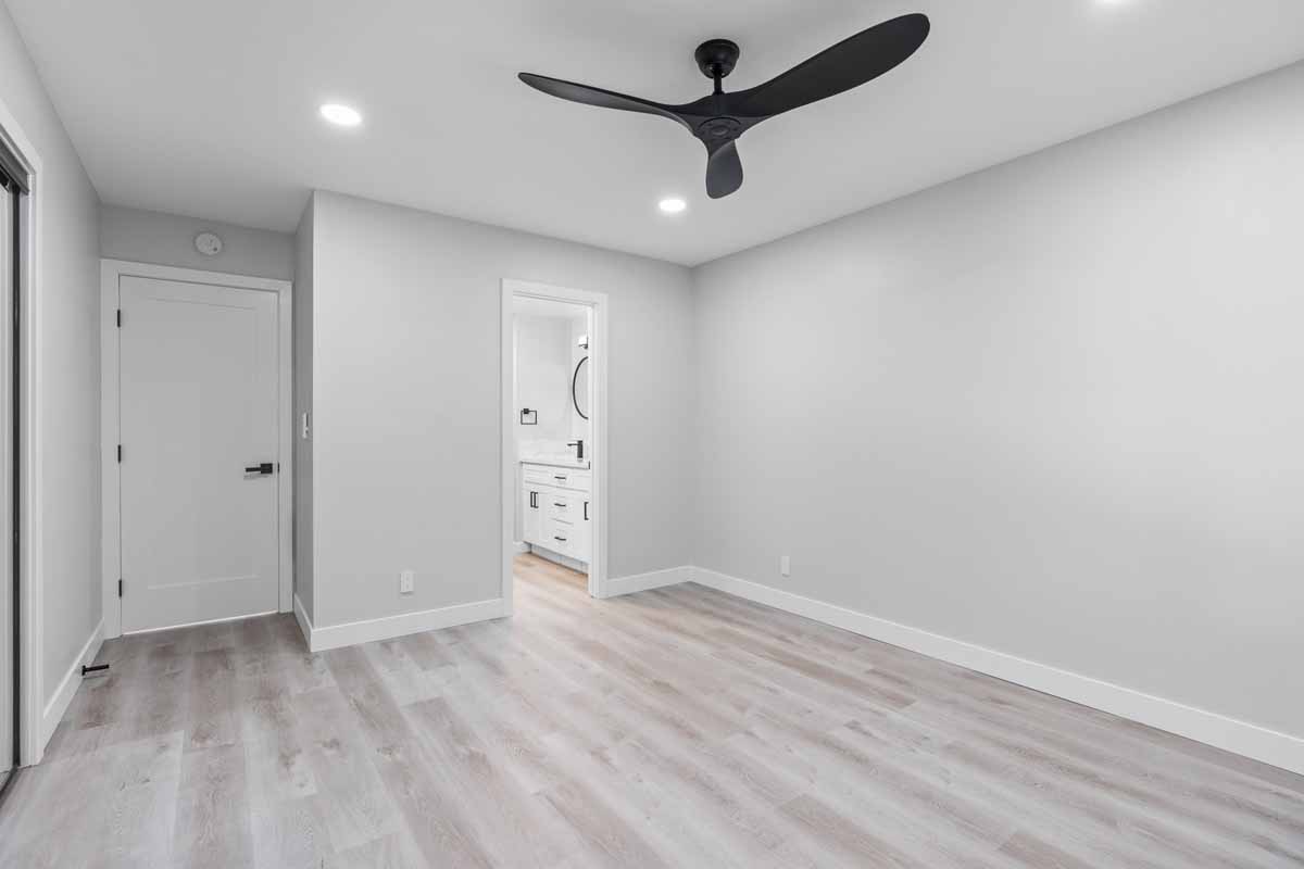 An updated empty bedroom with neutral toned walls and floors, and recessed lighting.