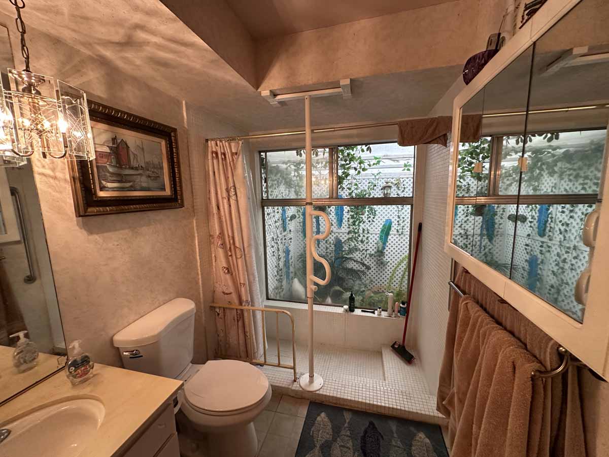 An outdated bathroom showing a sink, toilet and a walk-in shower.