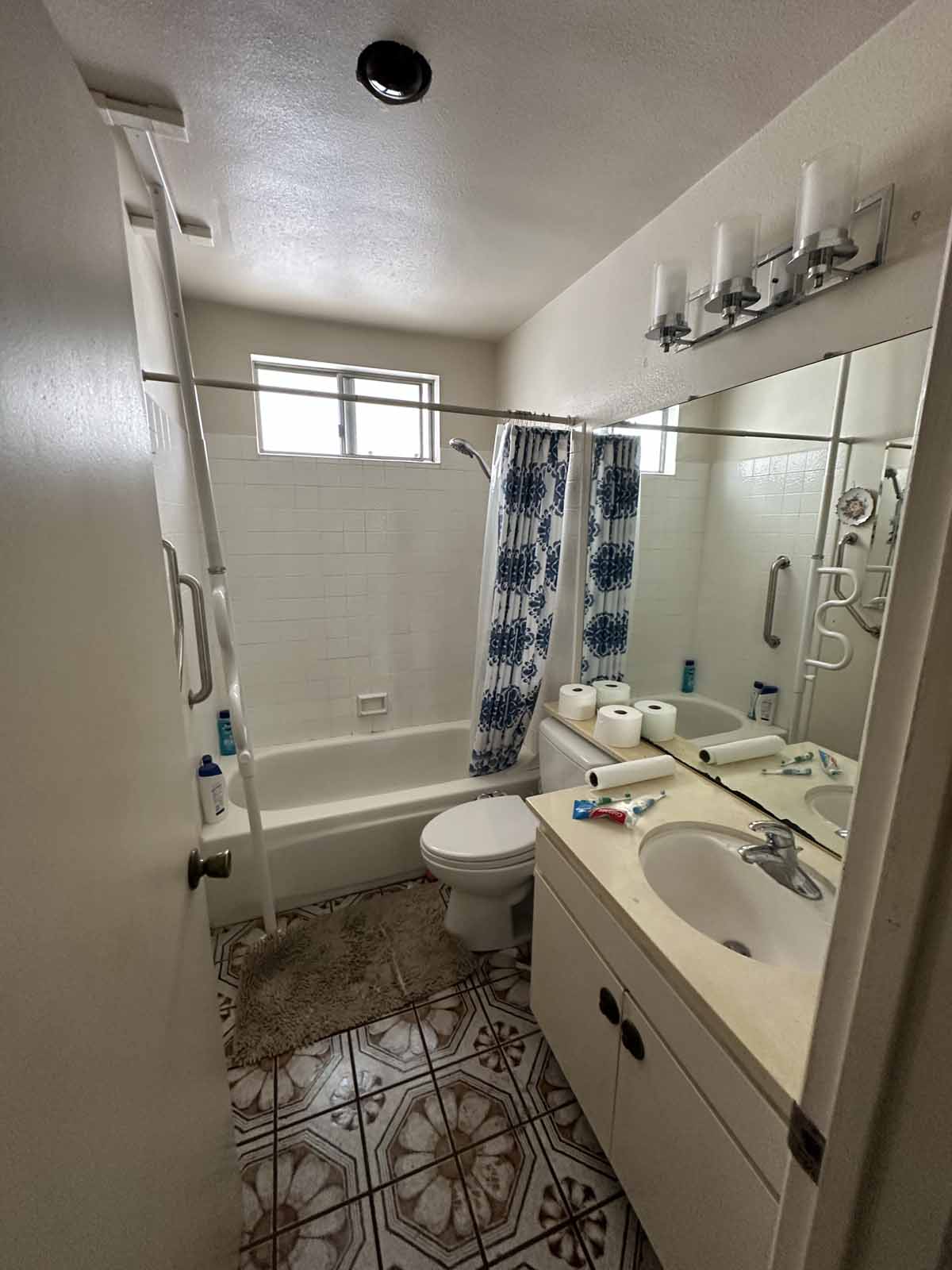 An outdated bathroom with tub/shower combo, toilet and single sink vanity.
