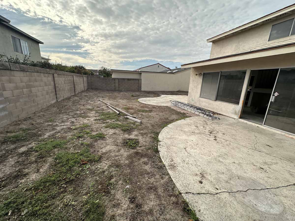 Backyard of home before renovation showing a large dirt lot.