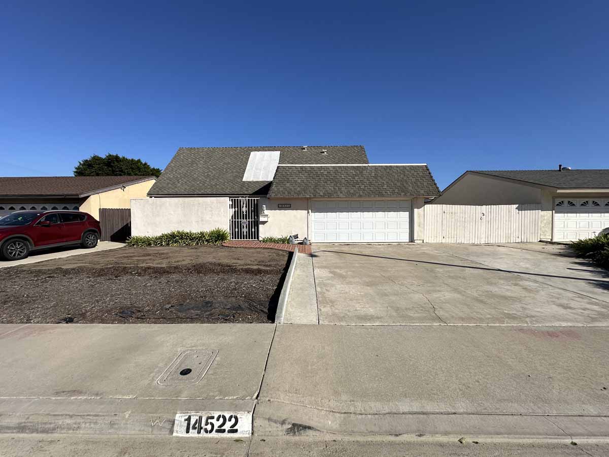 Front exterior of home with a large drive way, home is neutral colors with a gray roof.