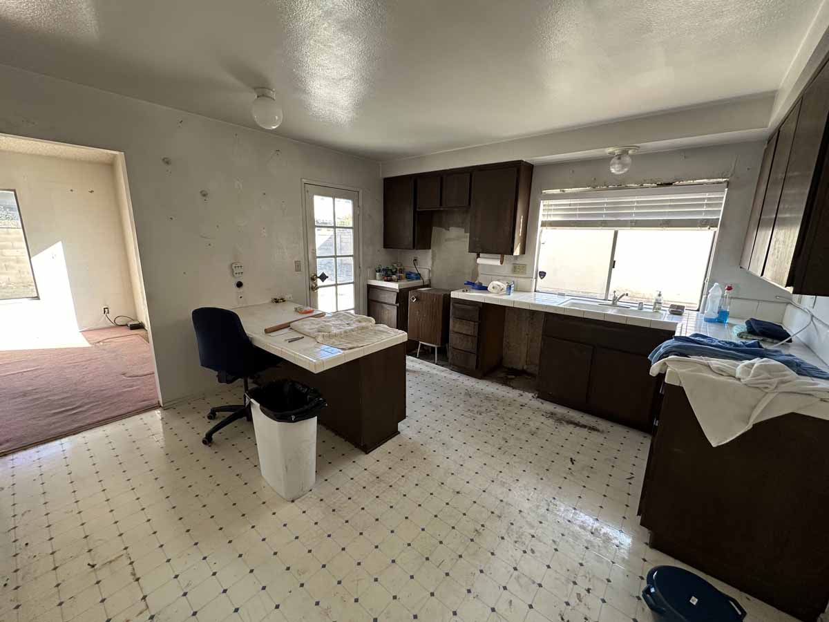 Outdated kitchen with white and black flooring, dark cabinets and light counter tops.