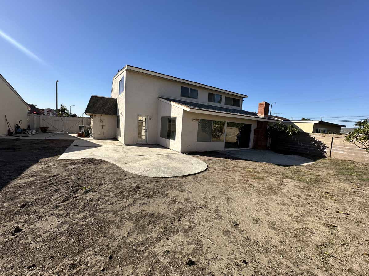 Backyard of home before renovation showing a large dirt lot.
