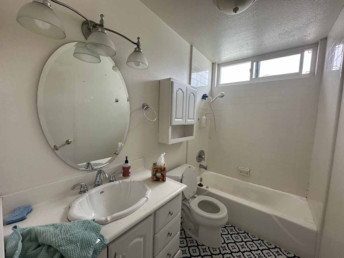 An outdated bathroom with a single sink vanity, toilet and a tub/shower combo.