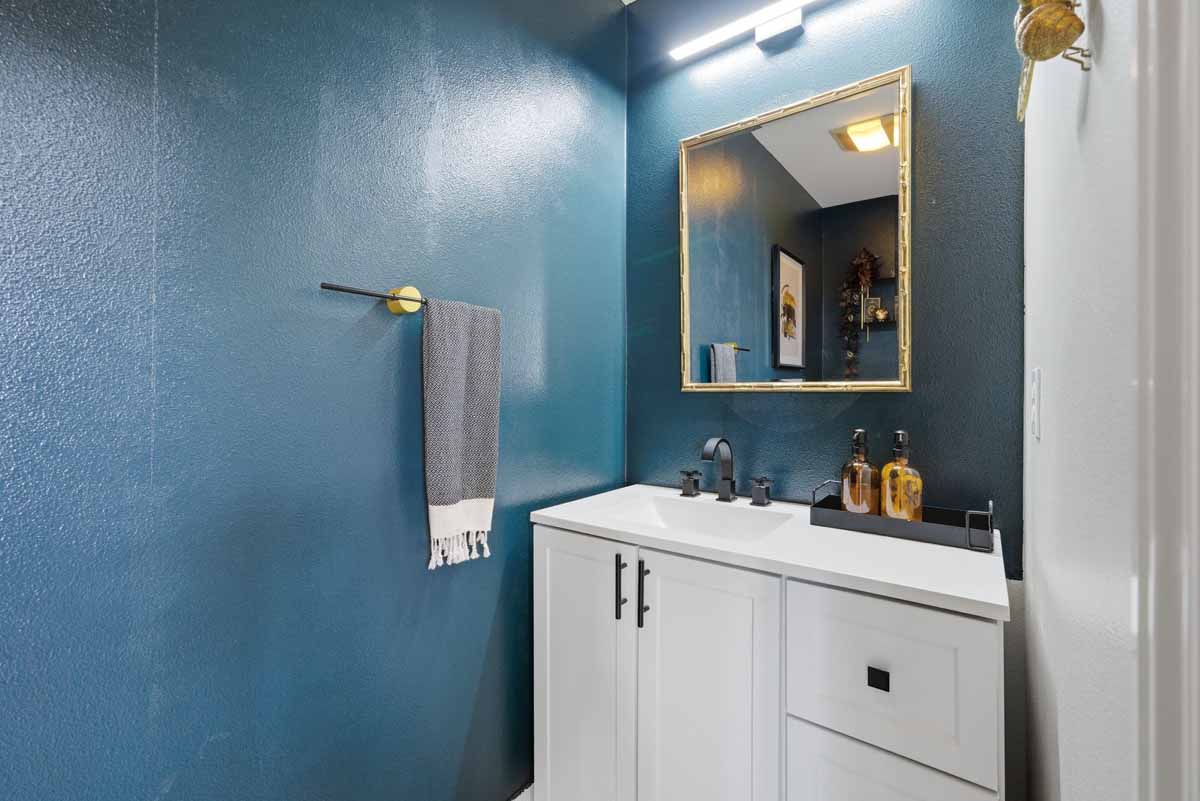 Blue painted walls with a white shaker-style cabinet in a half bathroom.