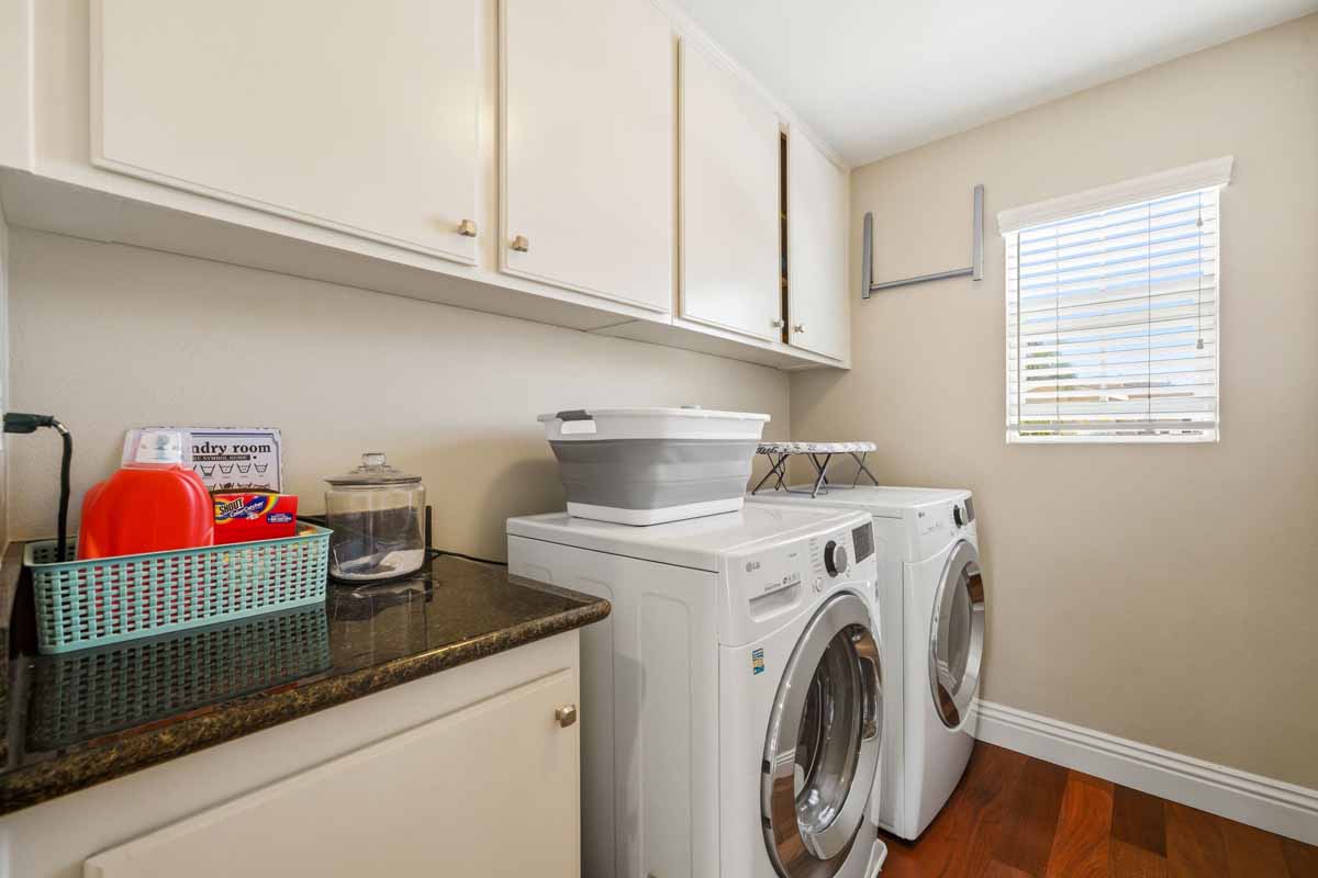 Laundry room with white cabinets and neutral colored walls.