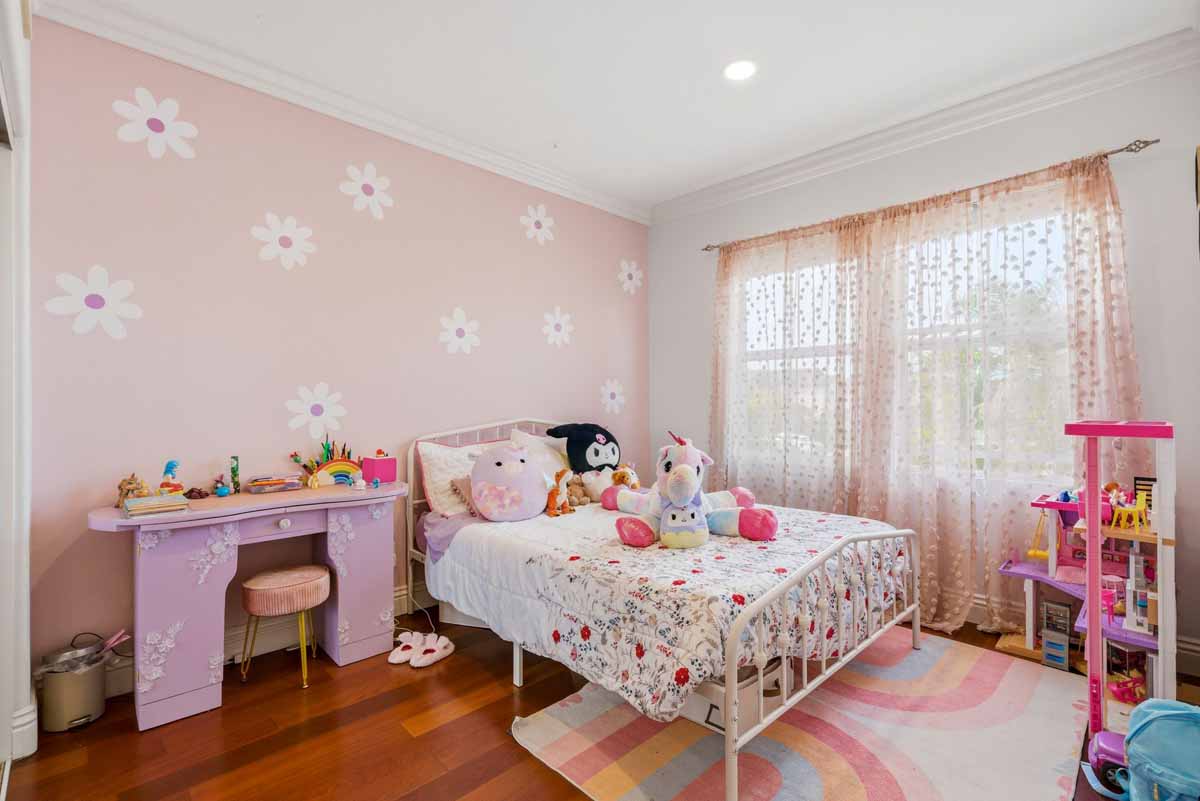 Little girl's bedroom with pink walls and wood plank flooring.