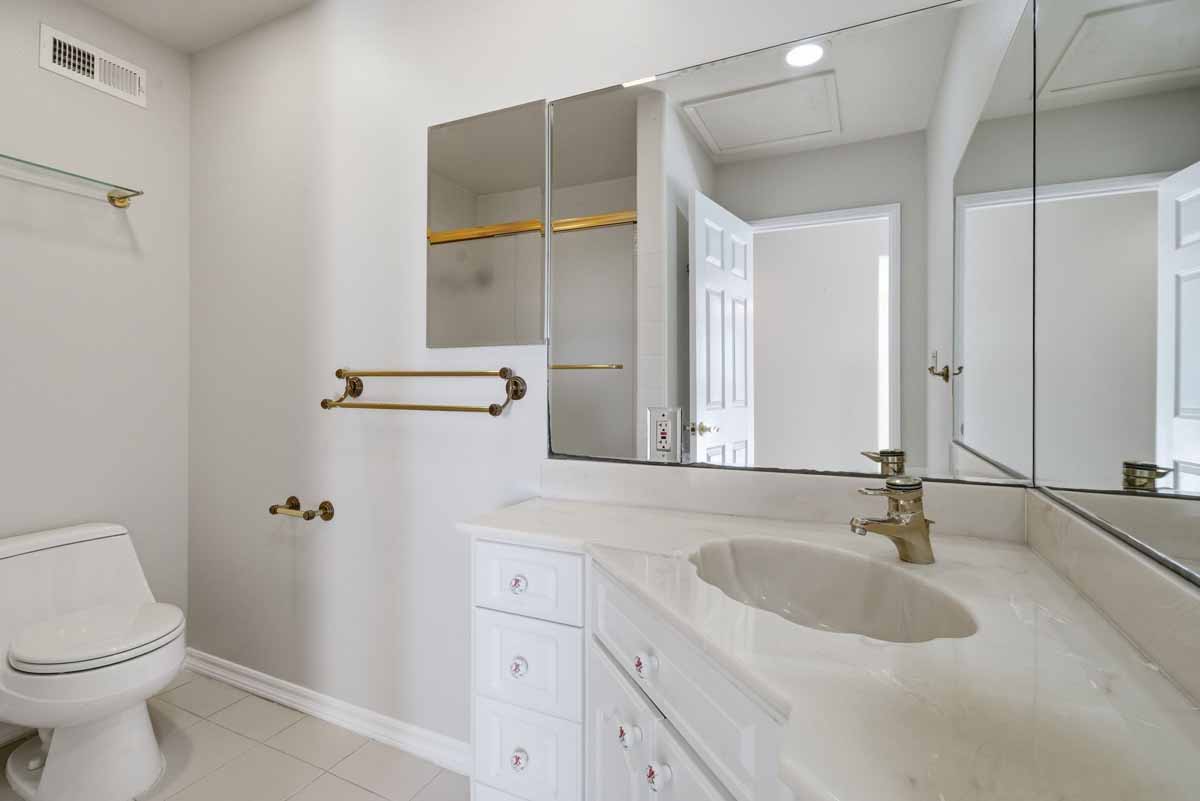 White bathroom with a vanity, sink and a mirror.