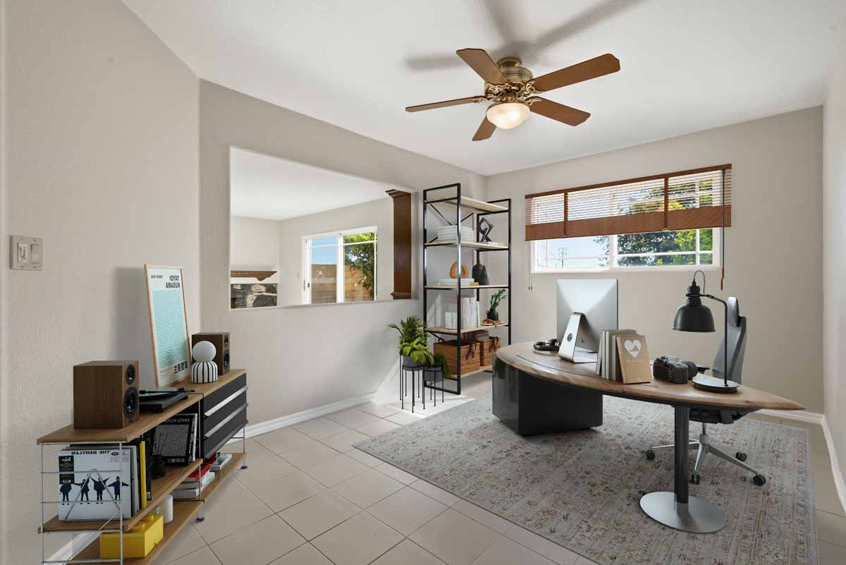 Digitally staged office space with work area and a peek-a-boo cut out through the wall looking towards the living room.
