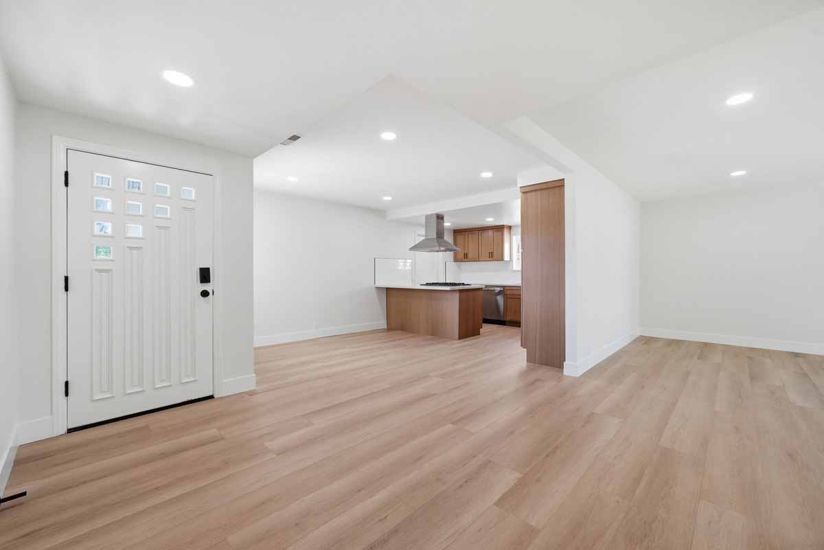 Entry way inside of 19562 Aragon Circle, Huntington Beach showing new light-wood flooring, recessed lights and the kitchen in the background.