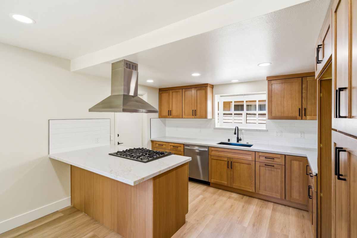 Updated kitchen with medium-toned wood cabinets and white quartz counter tops.