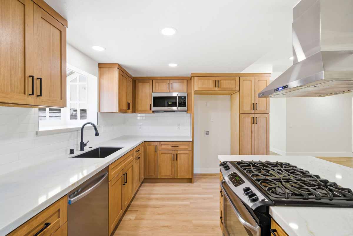Updated kitchen with medium-toned wood cabinets and white quartz counter tops.