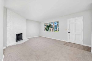 Updated living room with fresh, neutral colored wall paint and a white painted brick fireplace surround.