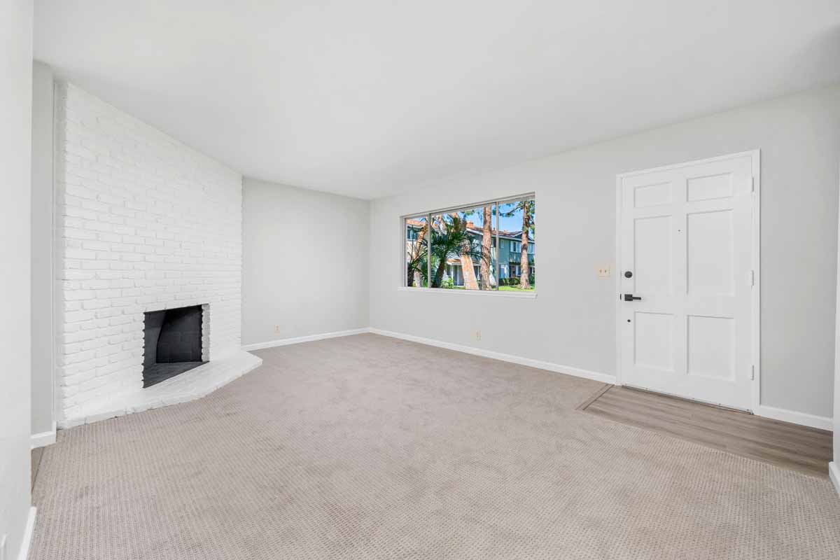 Updated living room with fresh, neutral colored wall paint and a white painted brick fireplace surround.