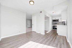 Bright dining area with new light colored wood flooring, neutral colored walls and a view to the kitchen.
