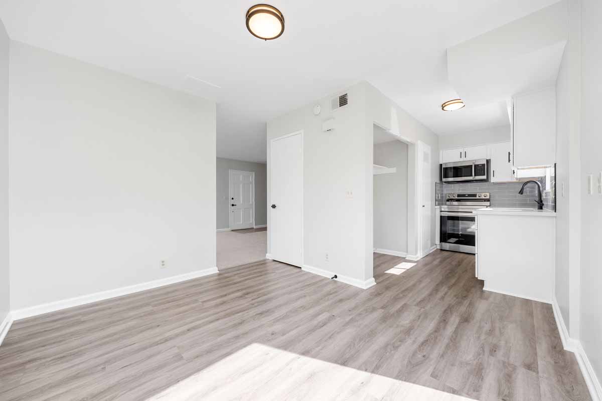 Bright dining area with new light colored wood flooring, neutral colored walls and a view to the kitchen.