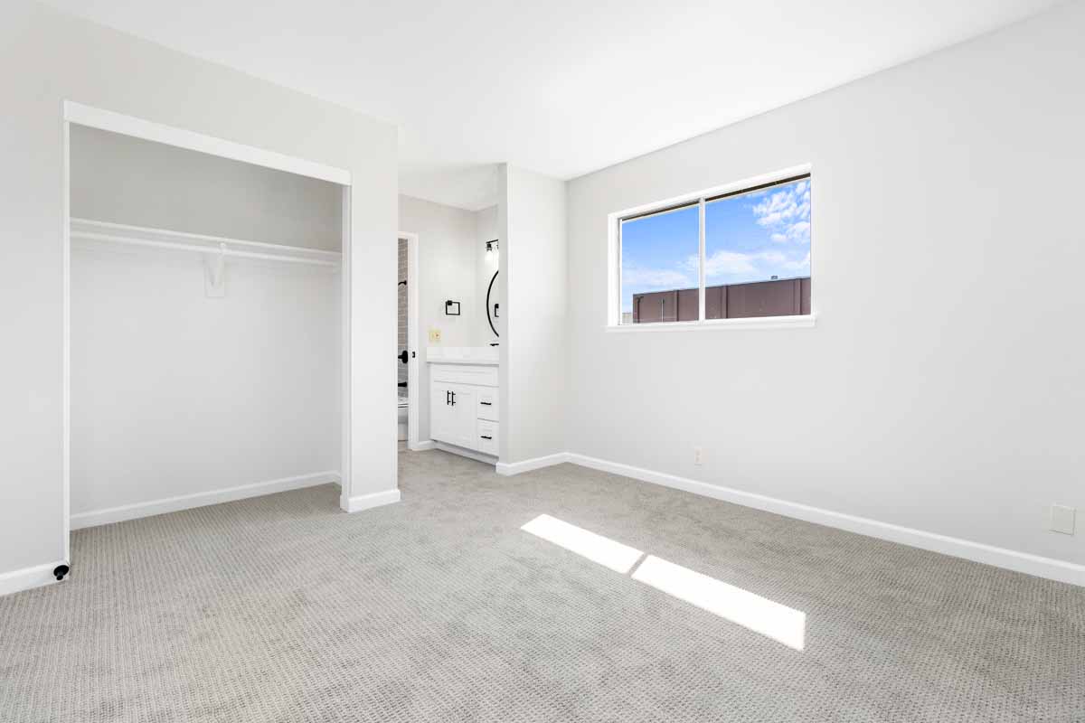 Bright, white, newly renovated bedroom with new light colored flooring, white walls and a small window.