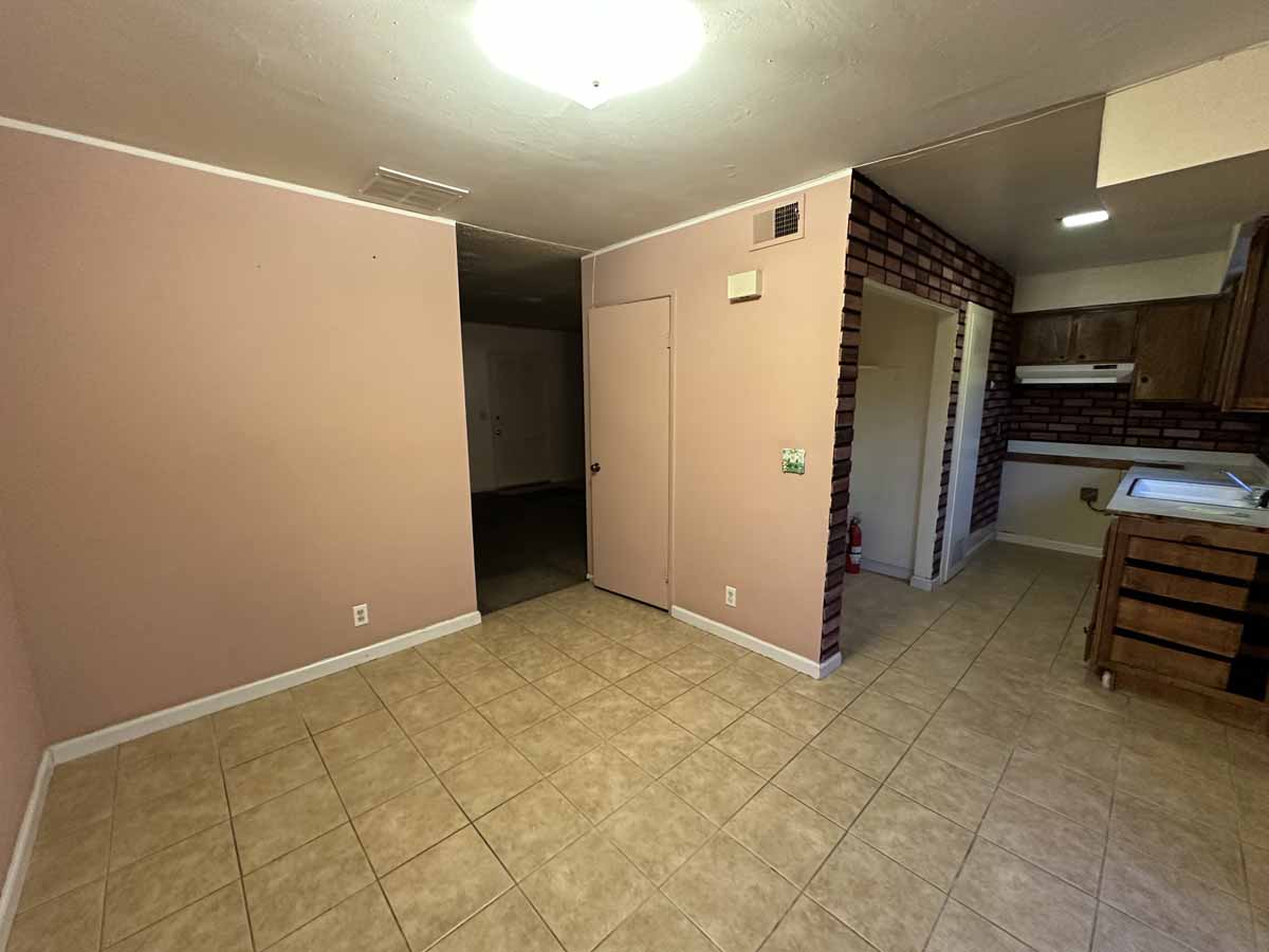Dark, outdated dining area with brown walls and beige tile flooring.