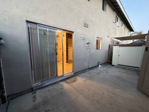 Tired patio with a sliding glass door showing old vertical blinds.