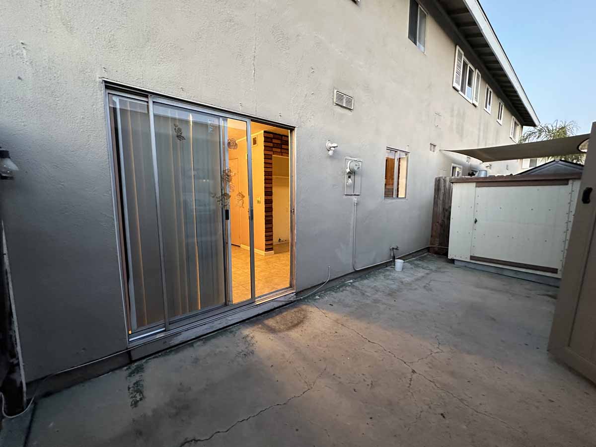 Tired patio with a sliding glass door showing old vertical blinds.