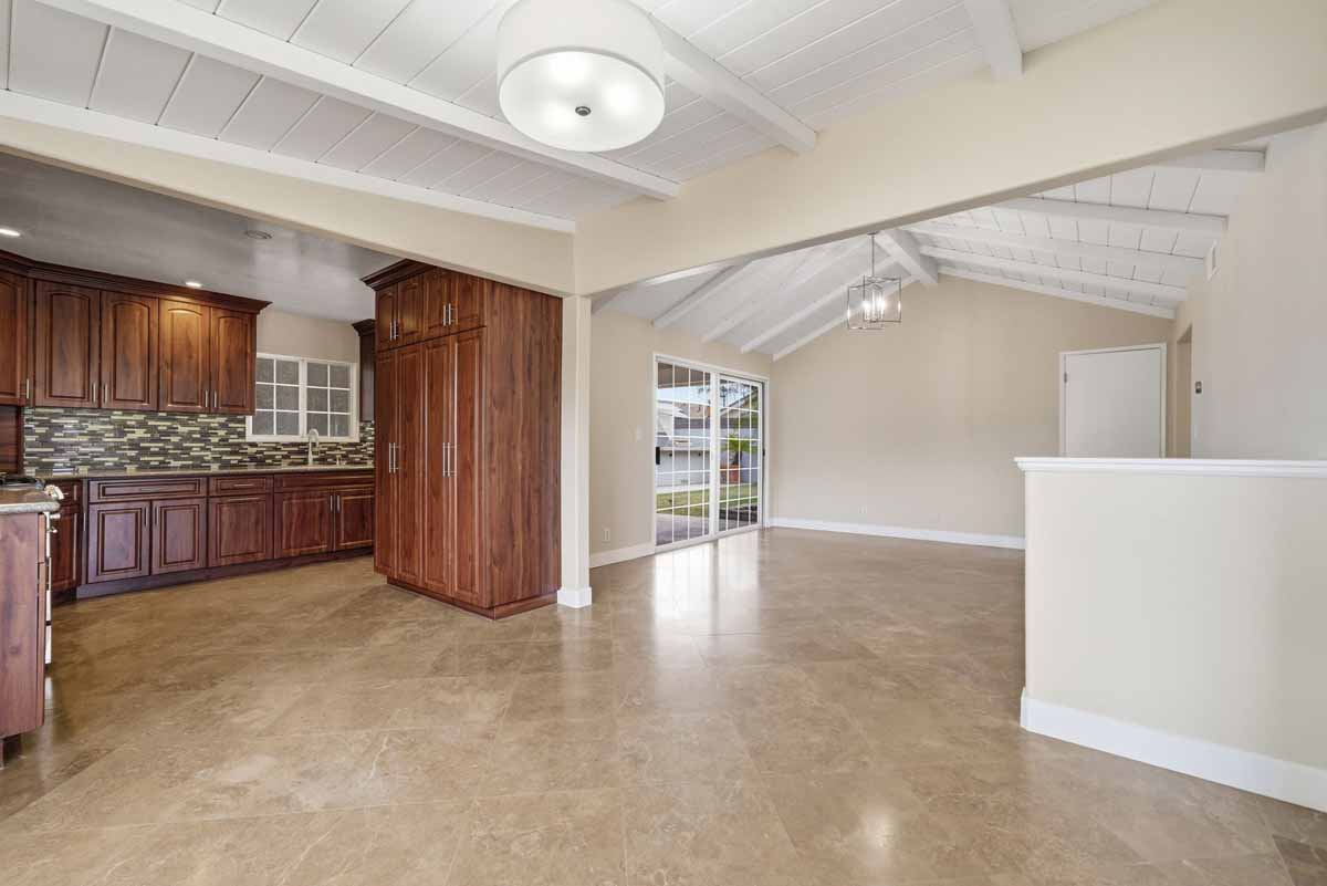 Dining area off the kitchen showing tan tiled flooring and white painted wood ceiling.