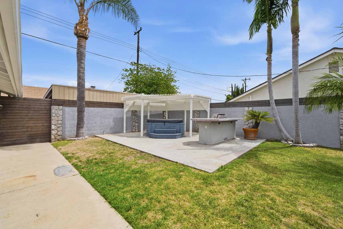 Backyard with a spa under a gazebo and a built-in barbecue.