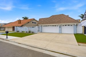 Front of a light blue painted house with a three car garage.
